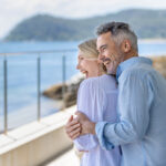 Couple walking along the Newcastle coastline discussing their comfortable retirement plan with Intentional Wealth.