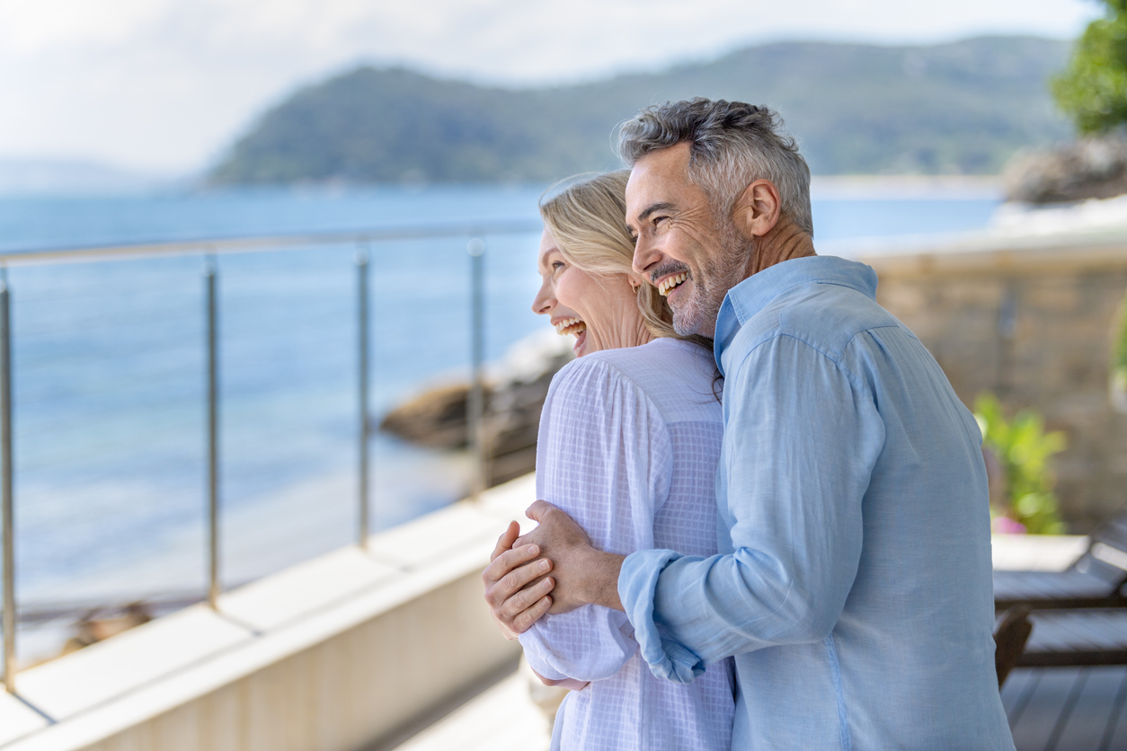 Couple walking along the Newcastle coastline discussing their comfortable retirement plan with Intentional Wealth.